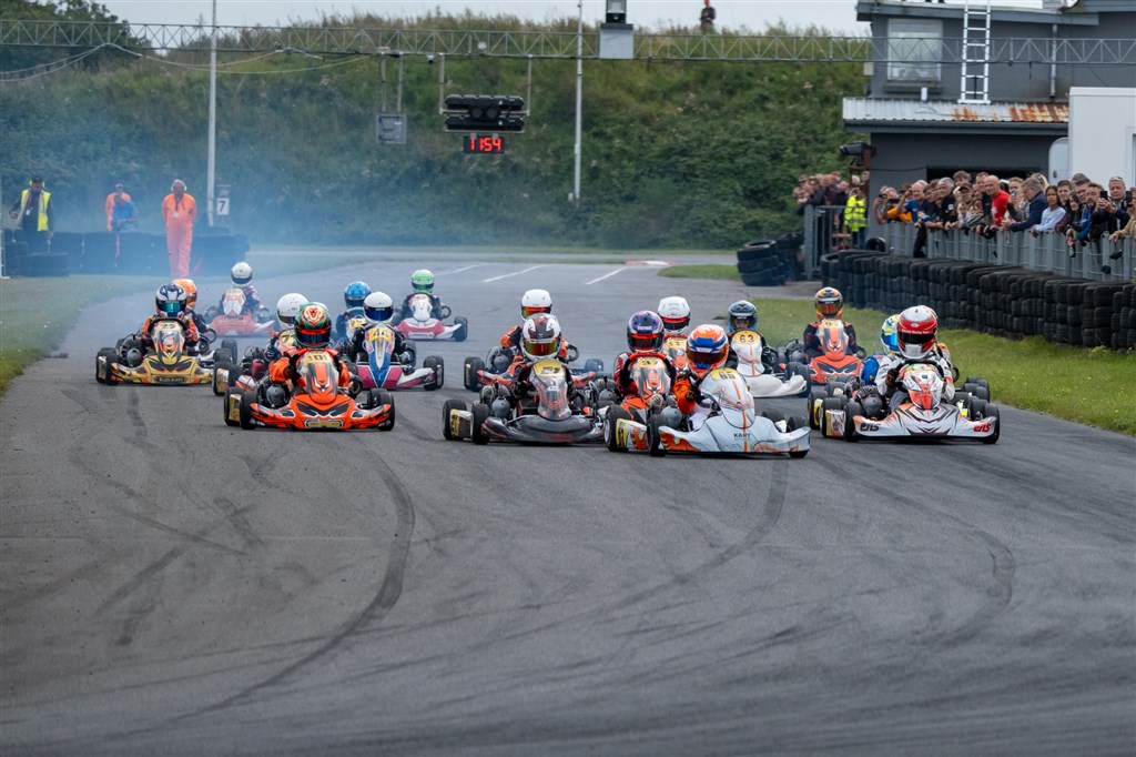 Tæt duel ind i sving 1 i Mini 60 – den senere mester Matteis Stigsen kører i Kart Republic-karten med #65.
(Foto: Niklas Majgaard, Boxengasse.dk/DanishKartingLeague)